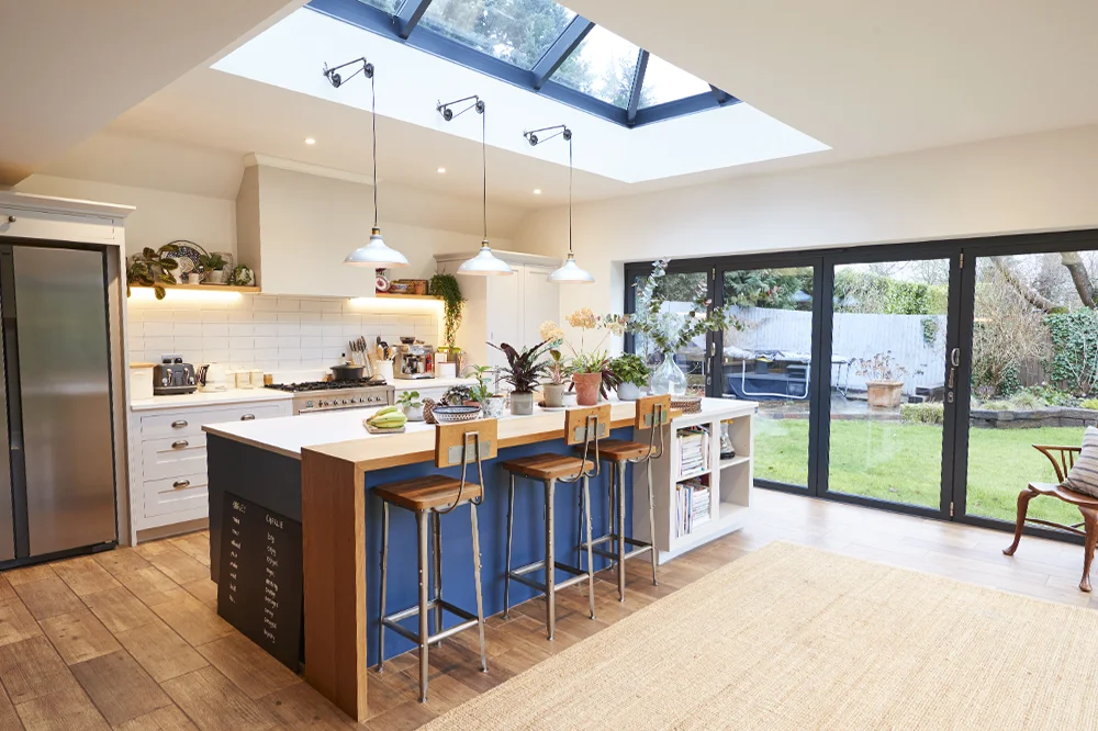 Kitchen island under a glazed roof lantern with bi-fold doors